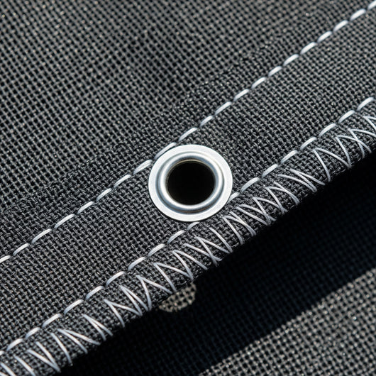 Close-up of gray shade cloth fabric with white stitching and a metal grommet.