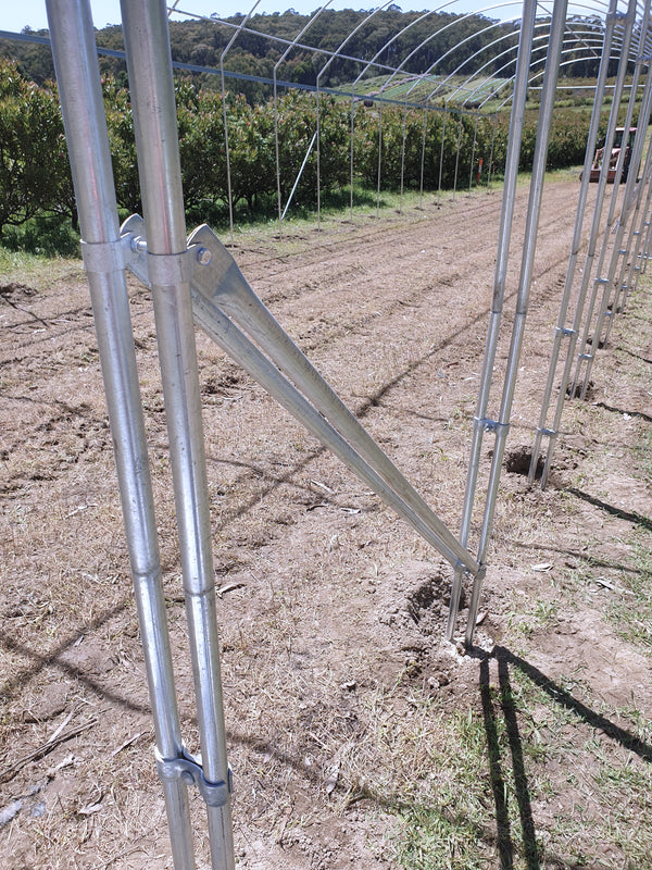 Metal agricultural frame in a field with trees in the background
