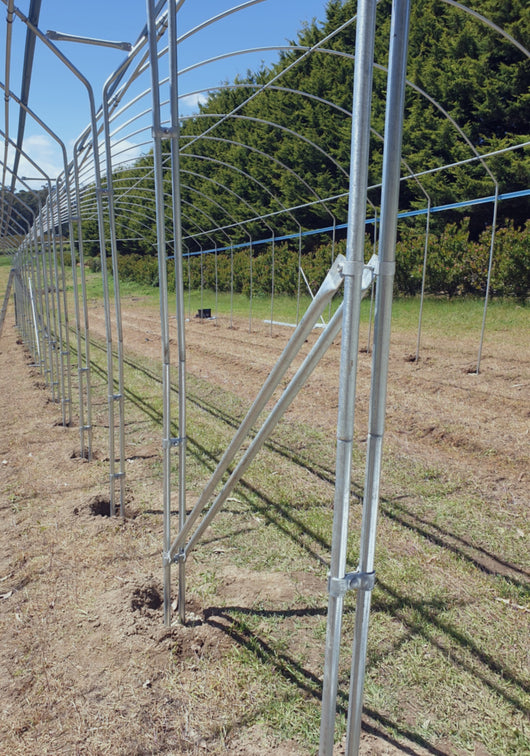 Metal frame structure in a field with trees in the background