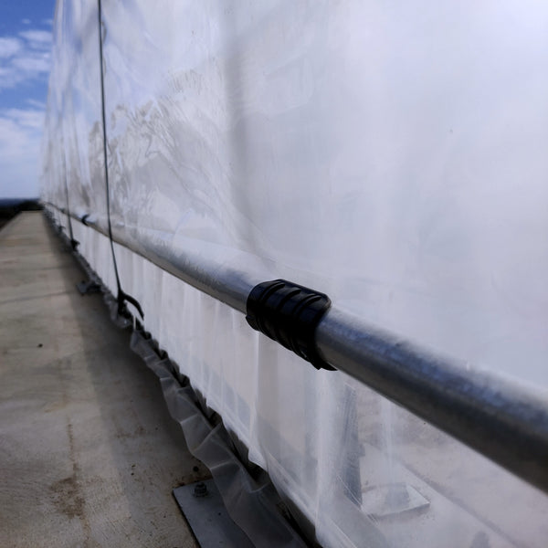 Close-up of a metal railing with a black tube clip and blue sky in the background